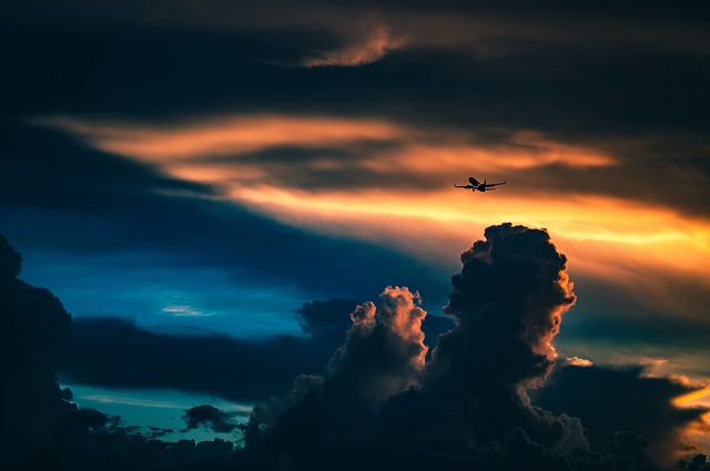 Dopravné lietadlo vo vzduchu medzi oblakmi pred slnkom.jpg